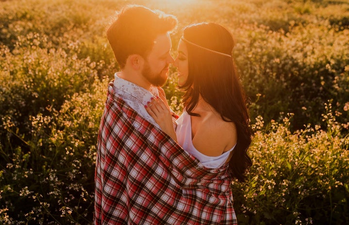 Young couple hugging at sunset in field