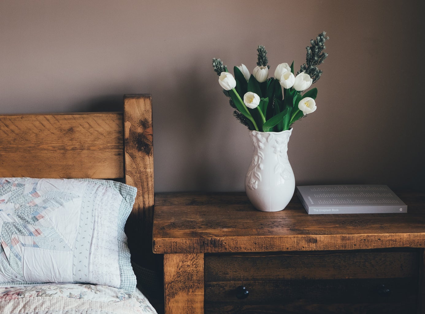 white flowers in vase on bedside table