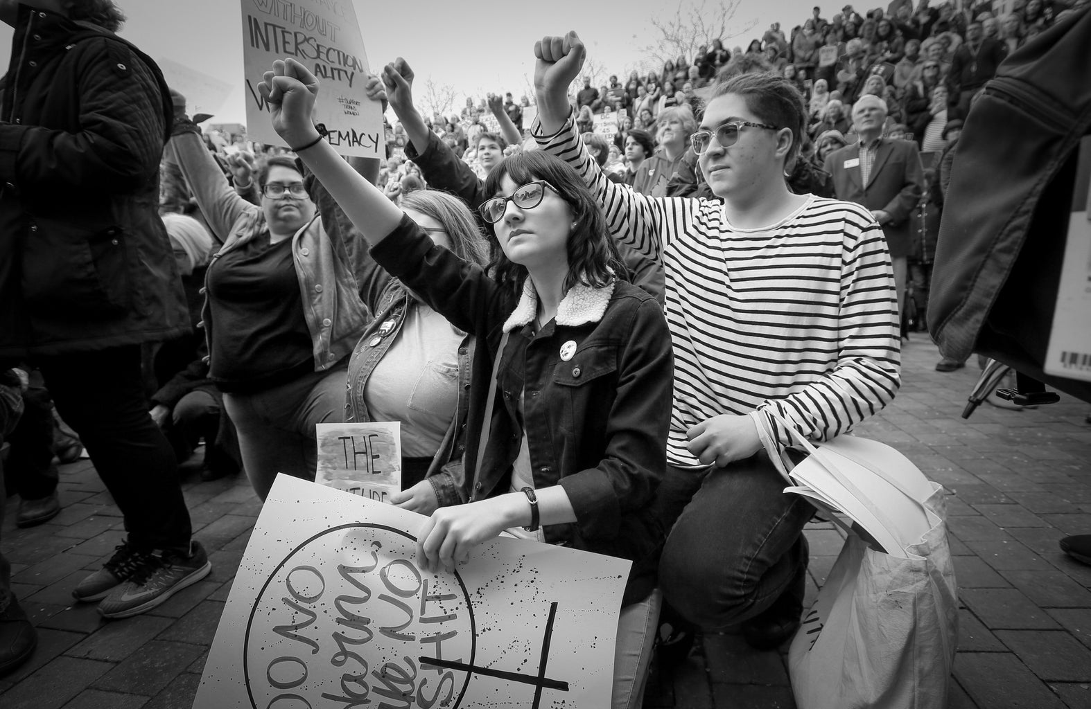 two women protesting on one knee with raised fists