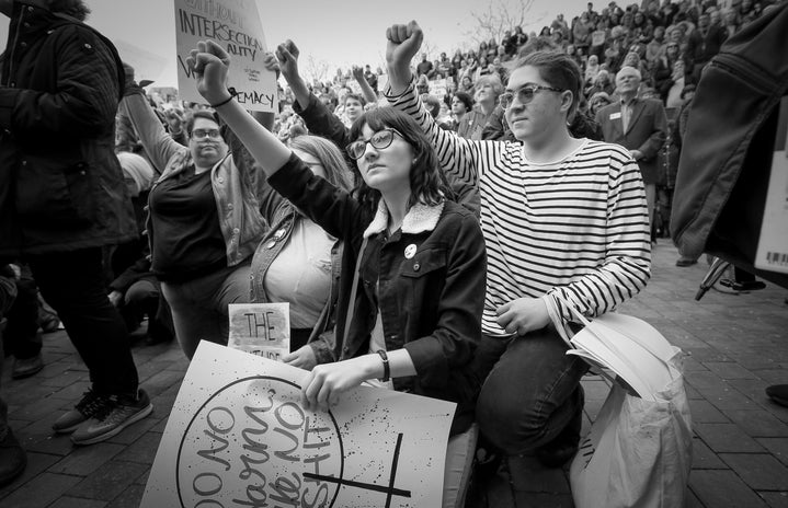 two women protesting on one knee with raised fists