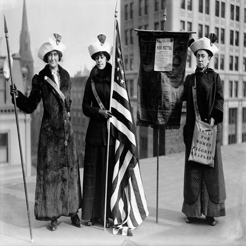 Women suffrage hikers General Rosalie Jones, Jessie Stubbs, and Colonel Ida Craft, who is wearing a bag labeled \"Votes for Women pilgrim leaflets\" and carrying a banner with a notice for a \"Woman Suffrage Party.