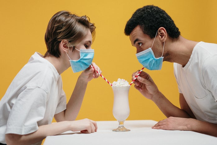 Couple wearing masks drinking a milkshake