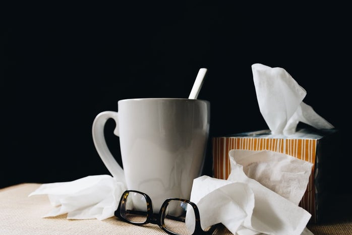 white coffee mug, black glasses, and a tissue box