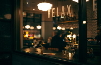Blurry photo of a person sitting in a restaurant with the words \"relax\" in the background