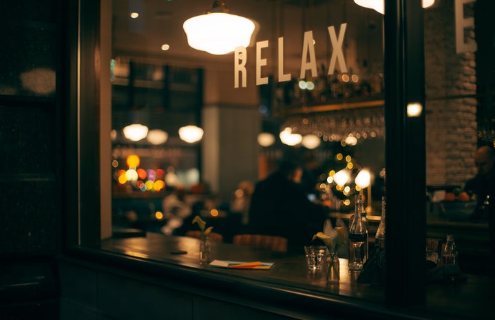 Blurry photo of a person sitting in a restaurant with the words \"relax\" in the background