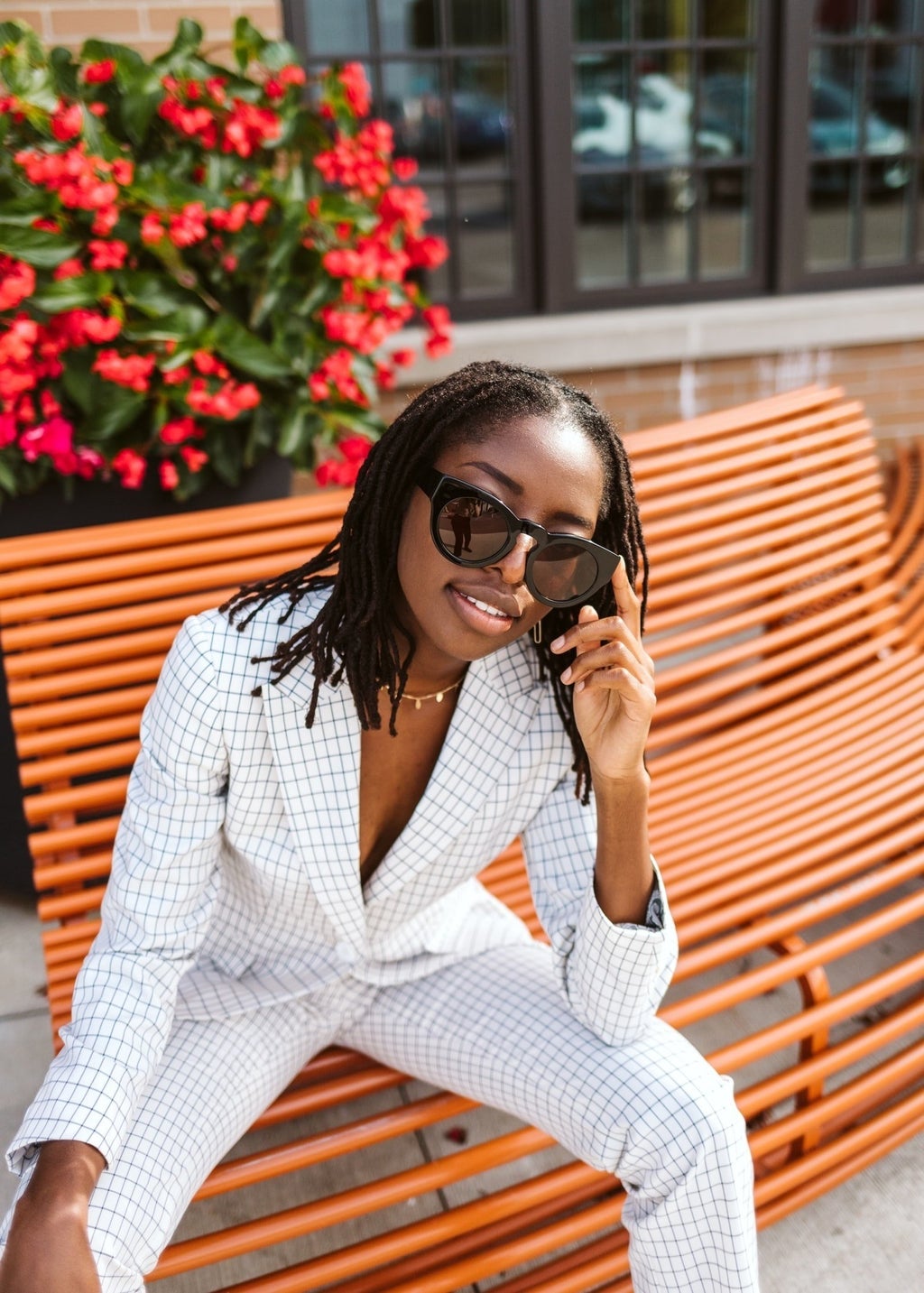 Woman in suit and sunglasses sitting on bench