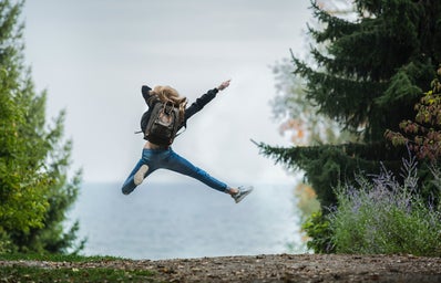 Woman jumping with green backpack