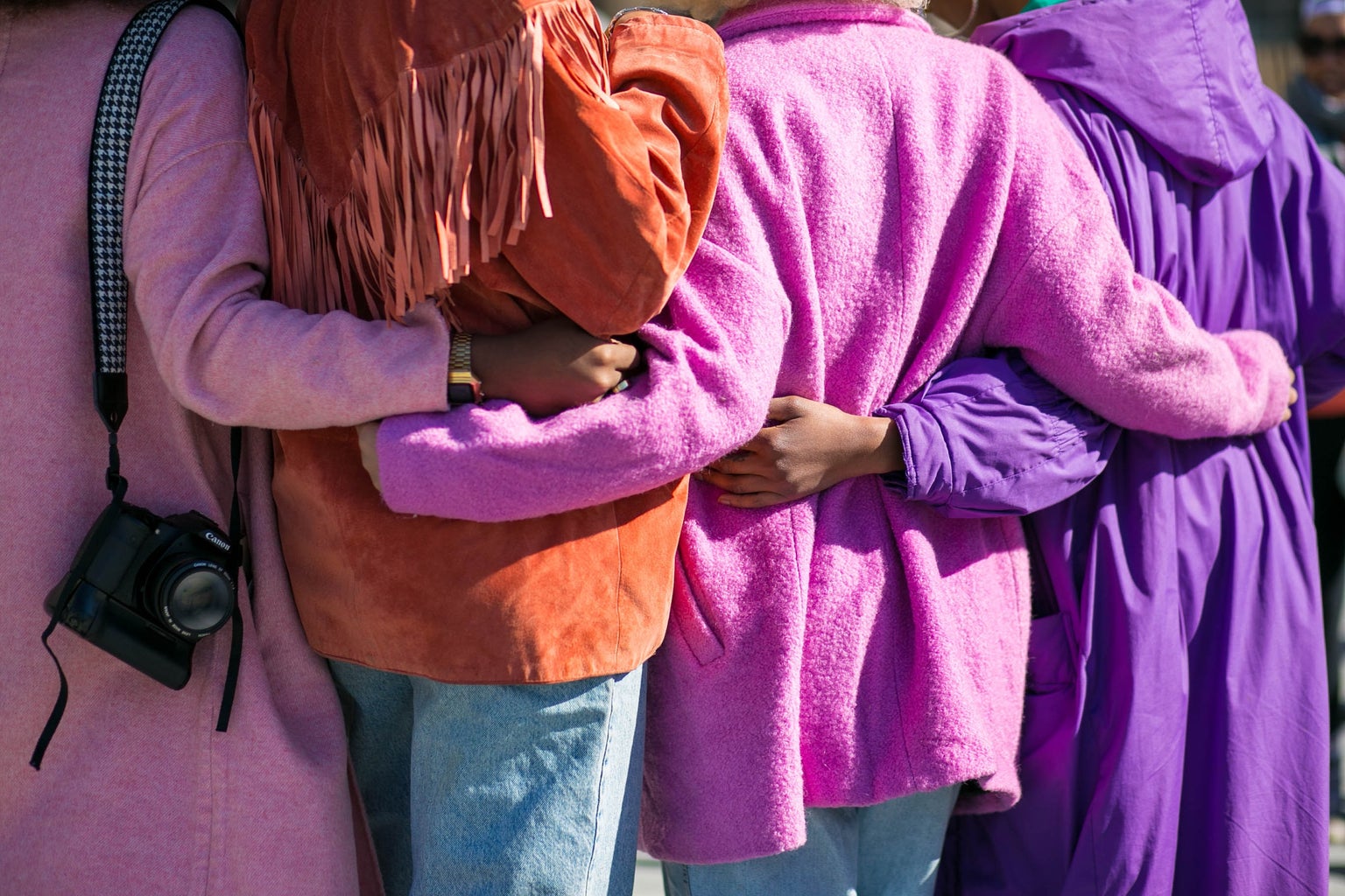 Four people hugging in really nice purple and orange jackets (no faces or legs included- just their backs)