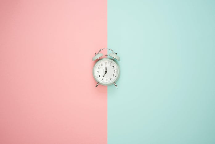 silver alarm clock on a pink and blue background