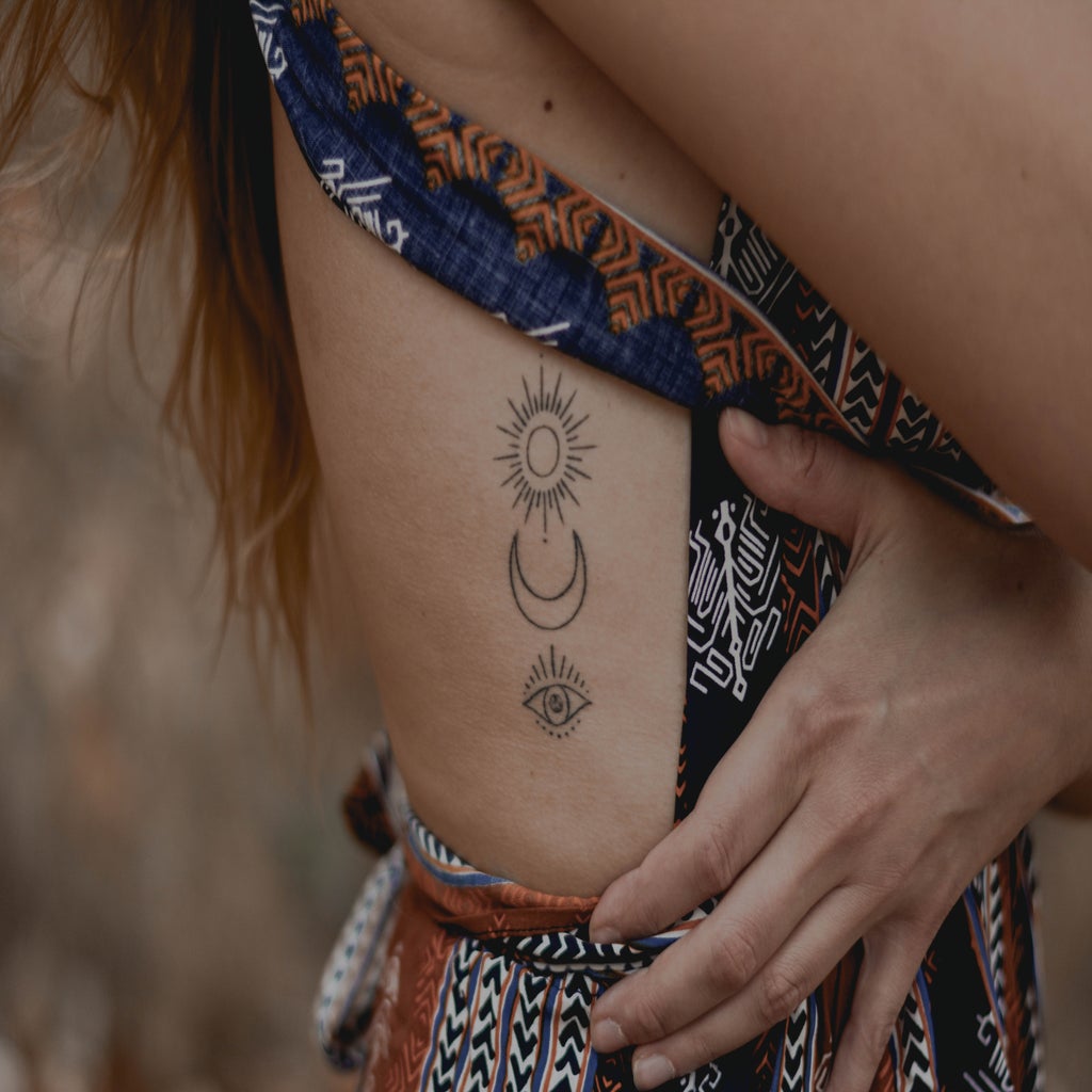 set of minimalistic tattoos on a person's ribcage