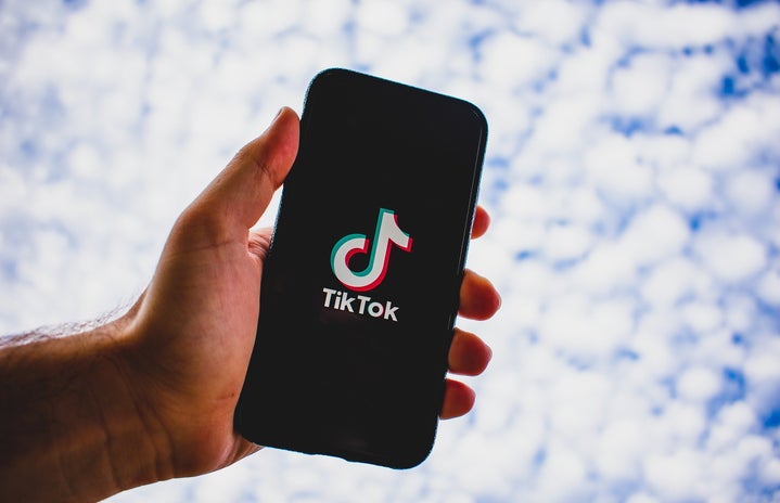 Person Holding TikTok with a Cloud Background