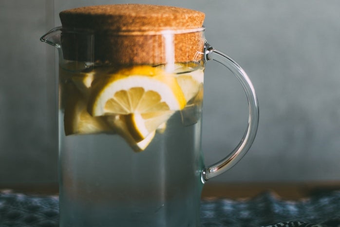 Lemons in water jug on table with cloth