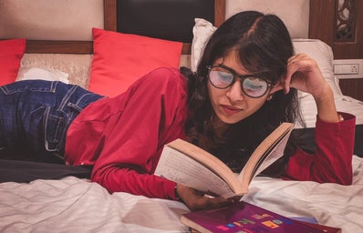 woman reading book in bed