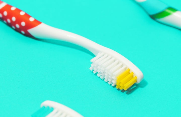 3 toothbrushes with a teal / turquoise background
