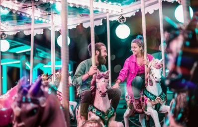 A man and woman ride on a colorful carousel.