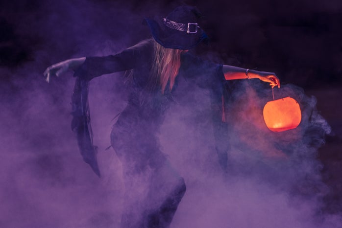 woman in witch costume surrounded by purple fog
