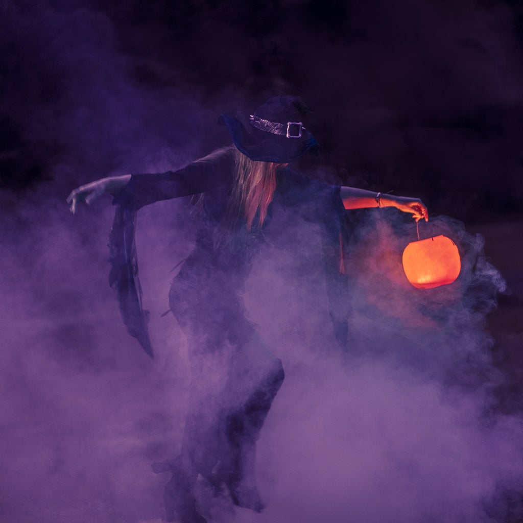 woman in witch costume surrounded by purple fog