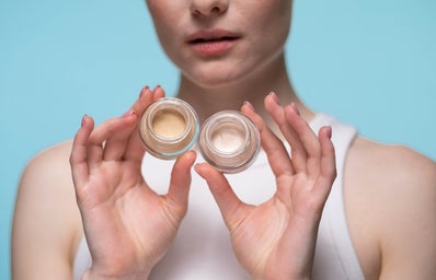 A lady holding two types of creams in her hands