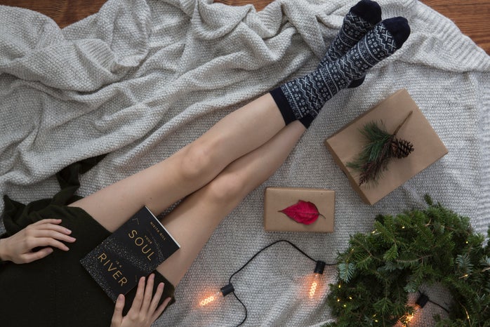 Girl reading next to present and holiday decor