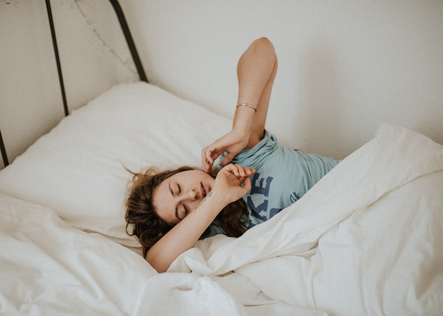 woman stretching in bed in sleepy daze