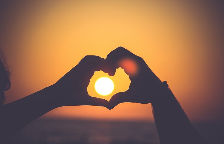 Hands making hearts at sunset