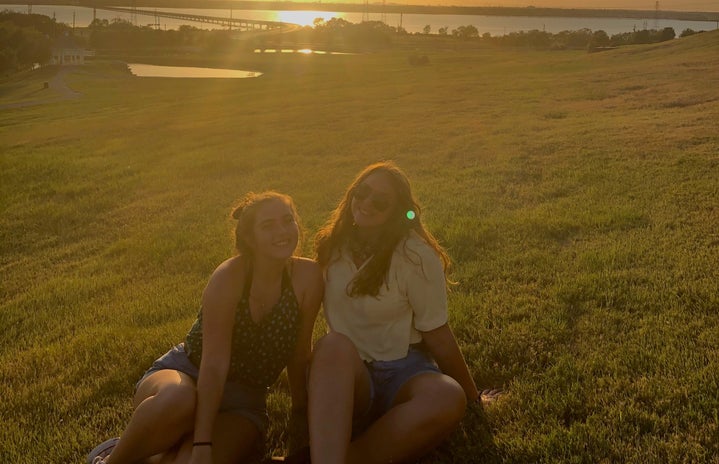 Two girls sitting by sunset