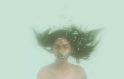 Girl underwater blows out air bubbles