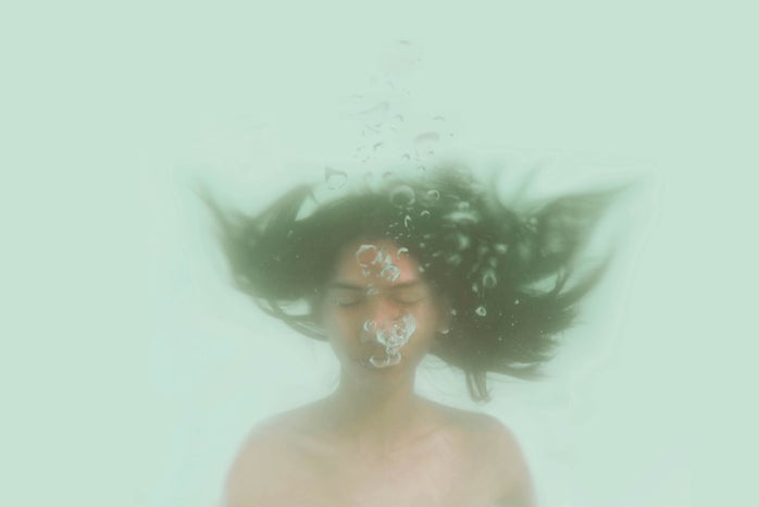 Girl underwater blows out air bubbles