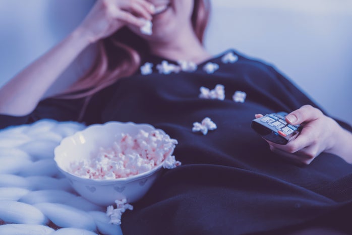 Woman lying on bed while eating popcorn