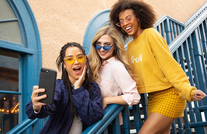 group of teenagers smiling at a cell phone