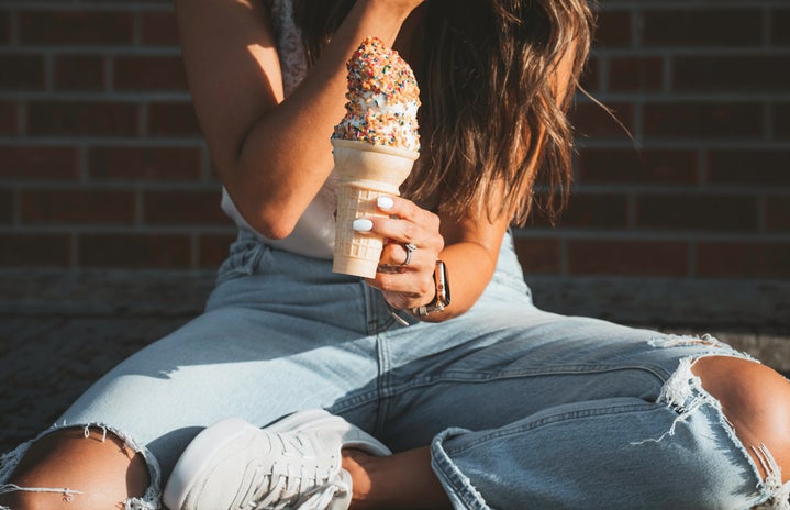 woman in jeans holding ice cream cone