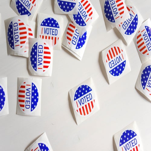 I Voted stickers scattered on a white surface