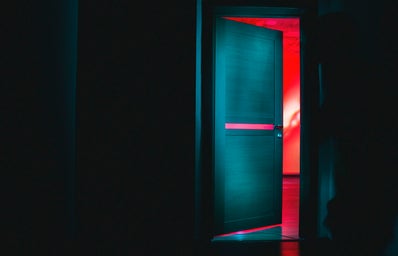 dark doorway opening into a room bathed in red light