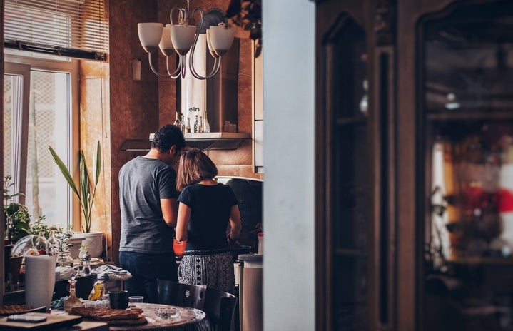 couple standing in front of stove in kitchen