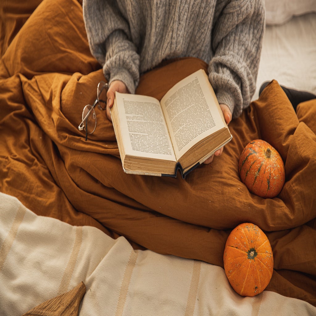 woman reading a book with pumpkins and fall colors