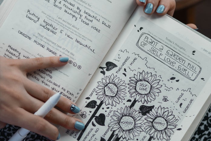 person holding a journal with drawings about self love