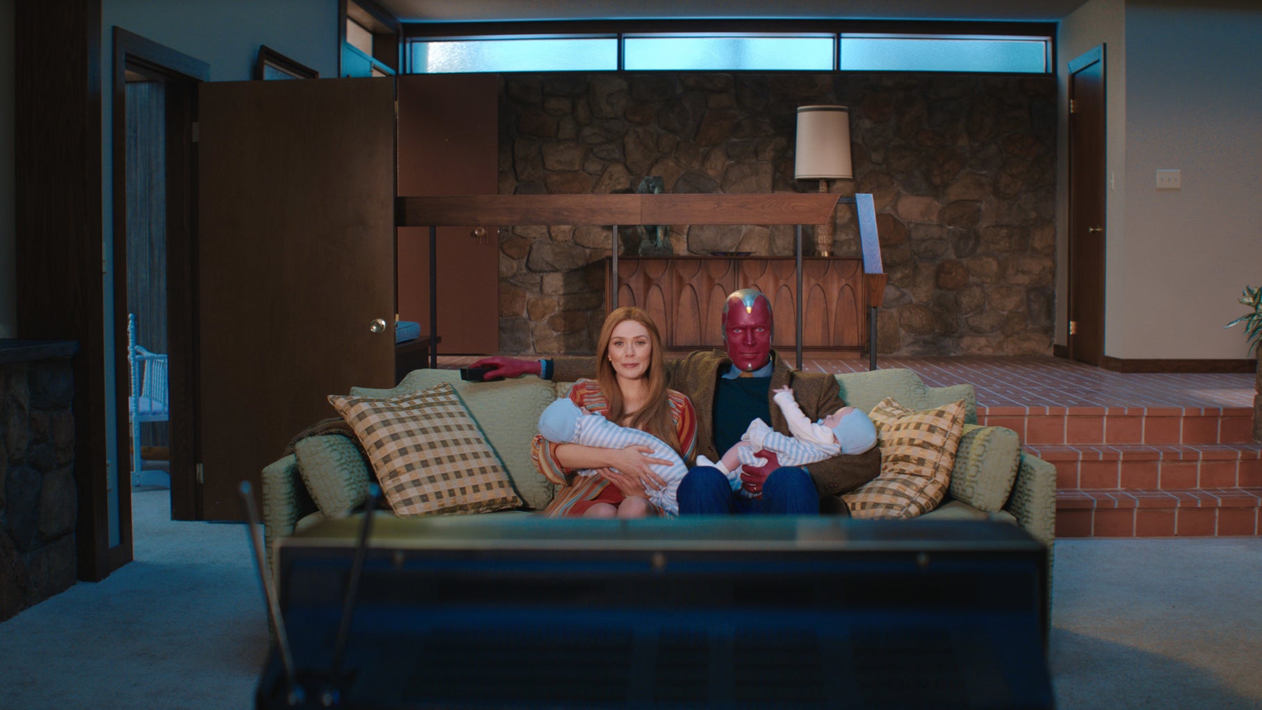 Wanda and Vision holding babies in front of a TV in Wandavision