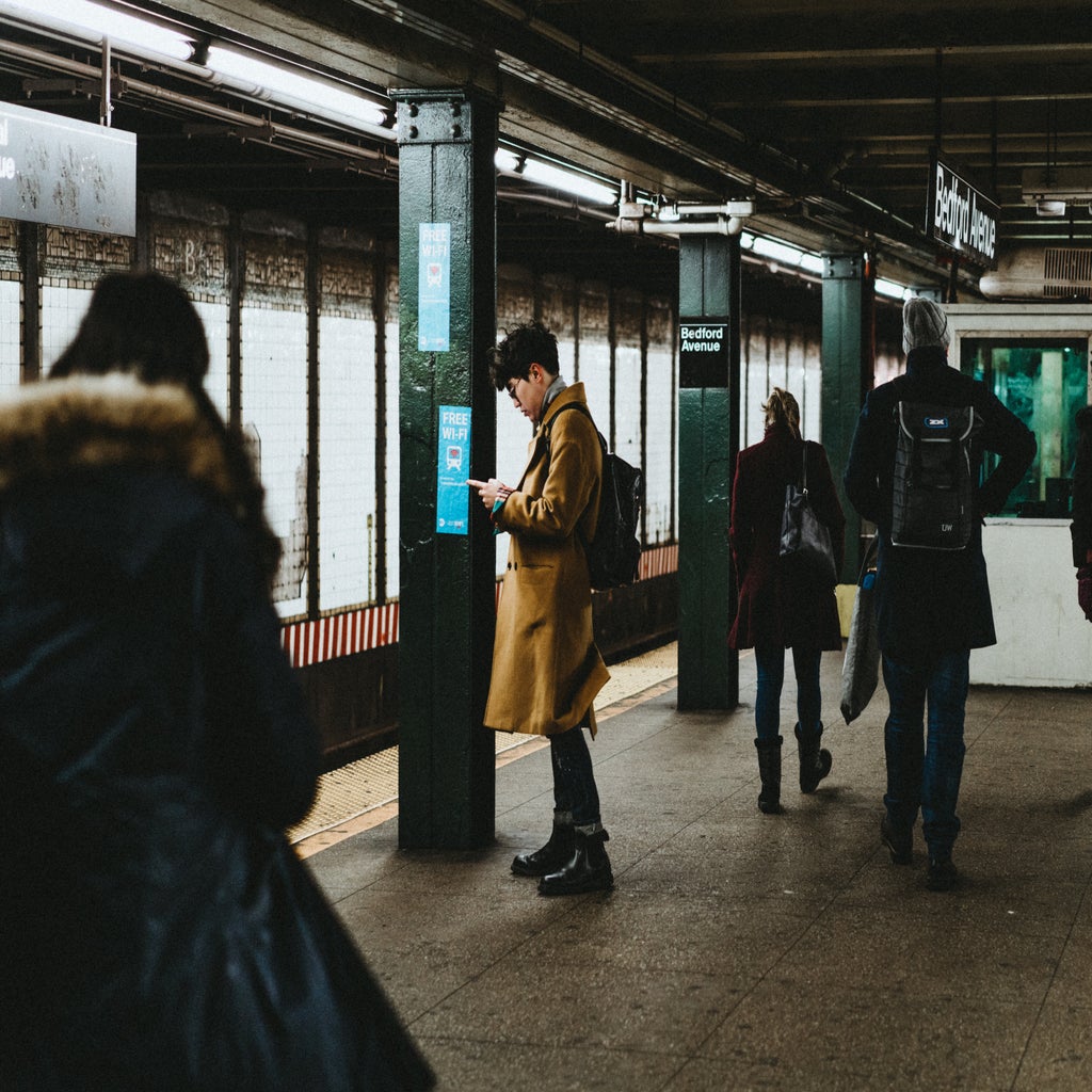 People on their phones, waiting for the next train on a subway platform