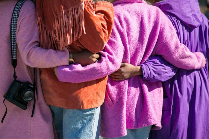 Four people holding each other in shades of purple