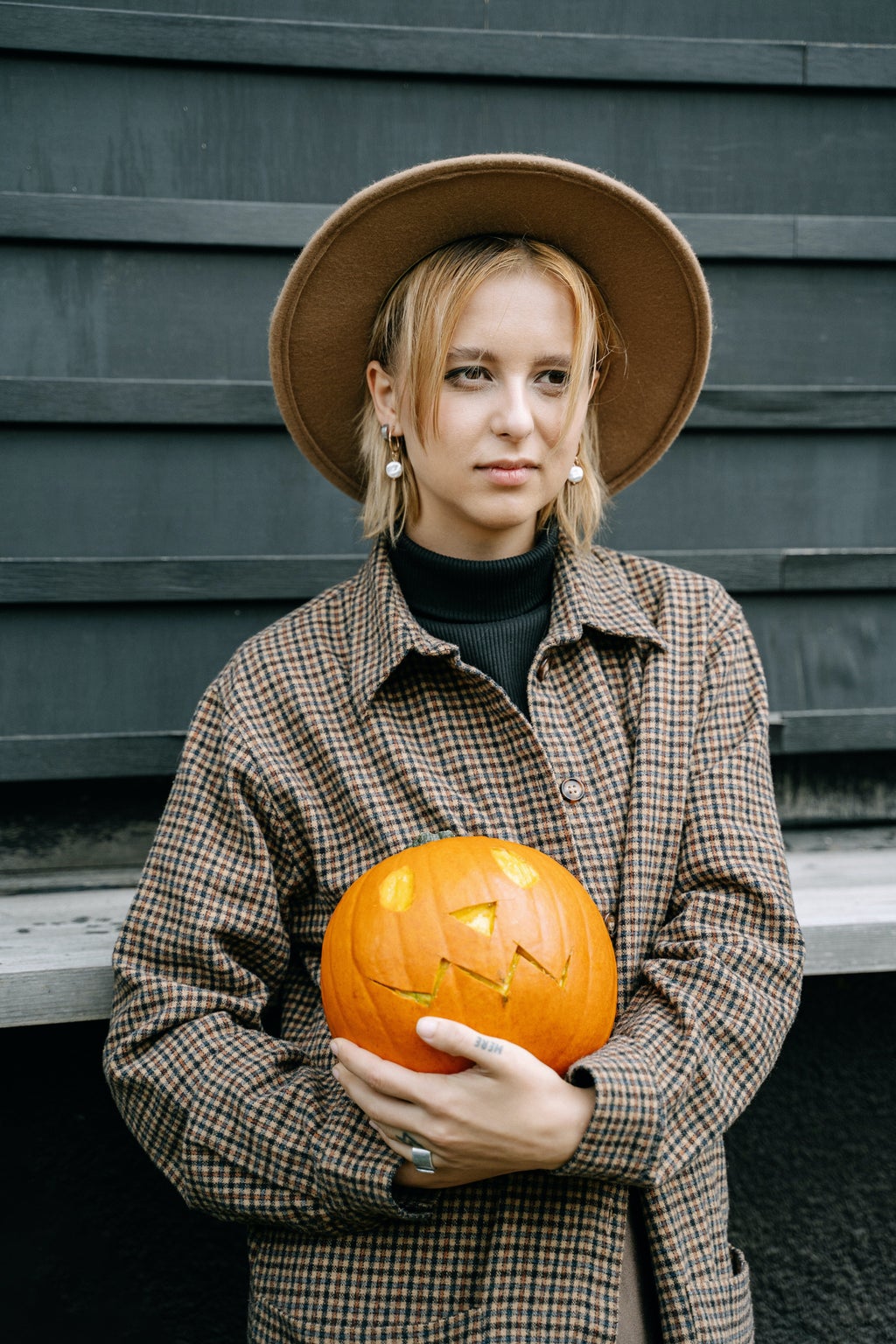 woman holding pumpkin and wearing fedora