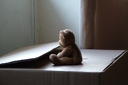 Sad teddy bear on moving box