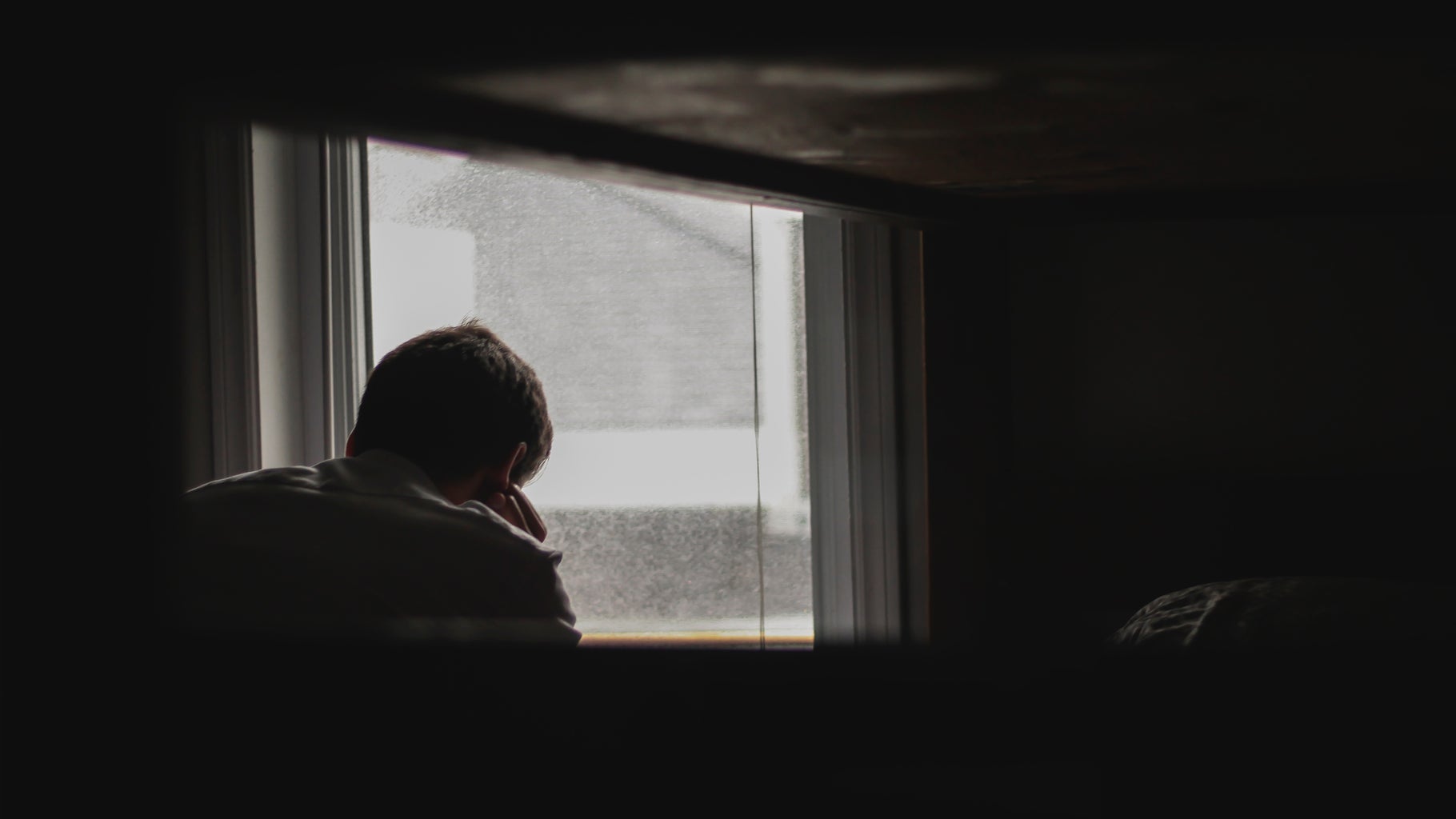 Person waiting by window, sad