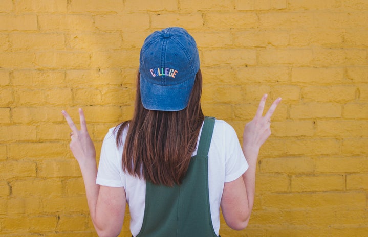 girl with blue college cap yellow wall