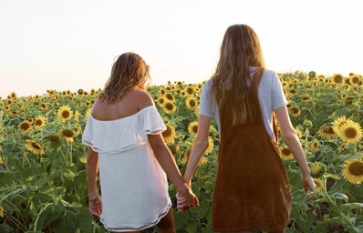 friends holding hands sunflower field dresses summer