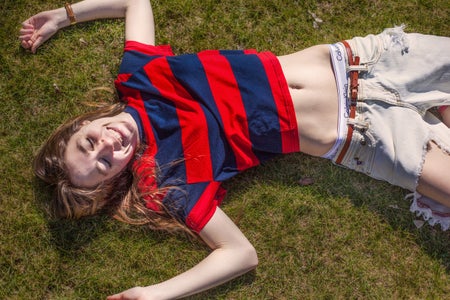 girl in sun in g rass ripped jeans