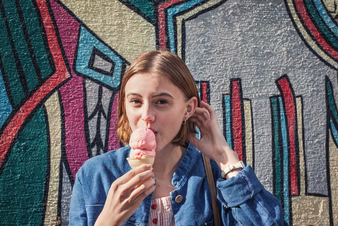 girl in front of colorful mural eating ice cream