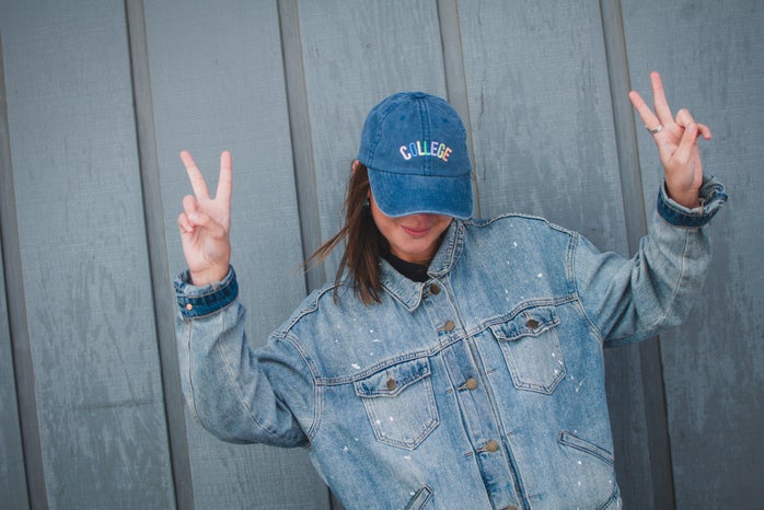 taylor thoman girl with jean jacket and collge hat peace sign?width=698&height=466&fit=crop&auto=webp