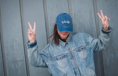 girl with jean jacket and collge hat peace sign