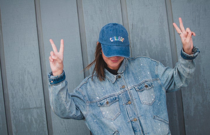 taylor thoman girl with jean jacket and collge hat peace sign?width=719&height=464&fit=crop&auto=webp