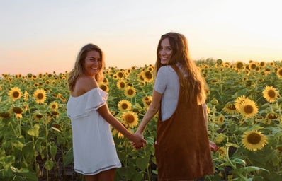 best friends holding hands sunflower field dresses summer happy sunset